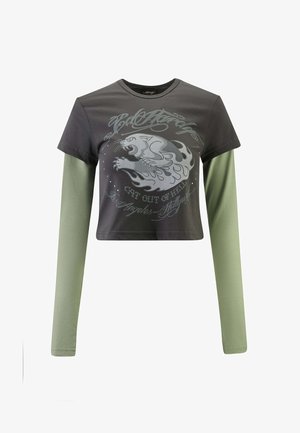 T-shirt cropped con corpo corto di colore grigio scuro e maniche lunghe di colore verde chiaro. Presenta una grafica frontale di un pantera con fiamme e testo.