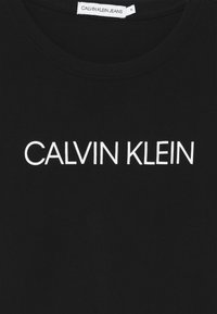 Černé bavlněné tričko s bílým logem "CALVIN KLEIN" vytištěným na hrudi. Klasický design s kulatým výstřihem. Měkká textura.