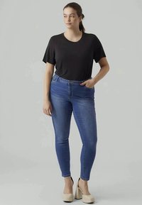 Μαύρο κοντομάνικο μπλουζάκι συνδυασμένο με ανοιχτό μπλε skinny τζιν. Τα τζιν διαθέτουν φερμουάρ και κλείσιμο με κουμπί μπροστά, ενώ το σύνολο ολοκληρώνεται με κρεμ χρώματος πλατφόρμες.