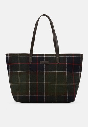 Sac fourre-tout avec un motif à carreaux vert foncé, rouge et blanc et deux bandoulières en cuir marron foncé sur un fond uni.
