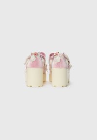 Roze fluwelen platform schoenen met een crèmekleurige zool, voorzien van bloemige versieringen zoals rozen, kant en kralen op de achterkant.