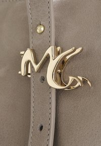 Borsa a mano in pelle beige con un evidente fermaglio a logo dorato, presenta una texture liscia e dettagli di cucitura decorativa.