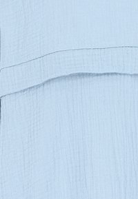 Hellblauer Stoff, strukturiert, mit einem geschichteten Design und einer weichen, zerknitterten Oberfläche. Keine sichtbaren Muster oder Hardware-Details.