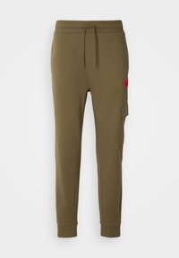 Pantalon de jogging vert olive à taille avec cordon, chevilles resserrées et poche cargo boutonnée sur la cuisse droite avec une étiquette rouge au-dessus.
