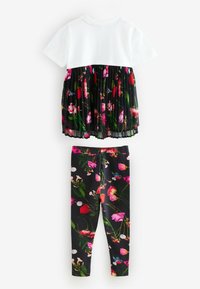 Kaksiosaline riietus, mis sisaldab valget puuvillast pluusi, plekitatud lillemustriga musta seeliku ja sobivaid musti retuuse, millel on erksat lillemuster.