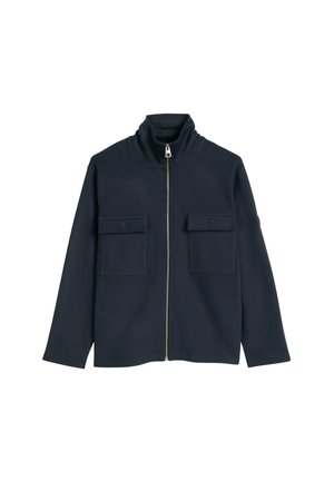 Dunkel marineblaue Jacke mit durchgehendem Frontreißverschluss, hohem Kragen und zwei mit Knöpfen verschlossenen Klappentaschen auf der Brust, flach liegend auf weißem Hintergrund dargestellt.