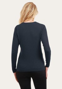 Pull marin à manches longues avec encolure arrondie, forme ajustée et texture lisse. L'ourlet est légèrement courbé ; les manches sont ajustées au poignet.