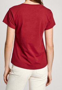 Röd bomullströja med korta ärmar och rundad halsringning. Slät textur, enkel design och en något avslappnad passform.