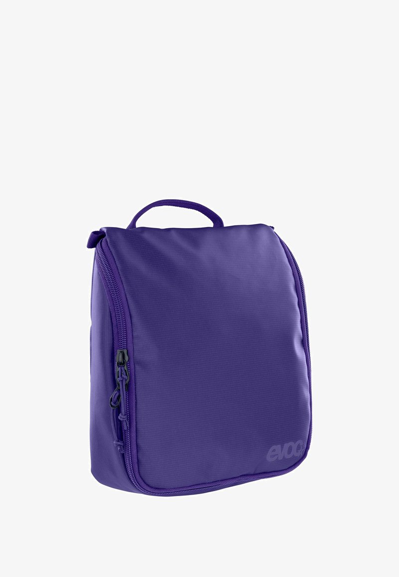 Mochila aislante de color púrpura con superficie texturizada, cierre con cremallera y asa superior para transportar. Presenta una marca en la parte inferior derecha.