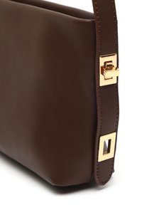 Borsa a mano in pelle marrone con una texture liscia, caratterizzata da un dettaglio in metallo dorato a forma quadrata sulla tracolla e un design minimalista.