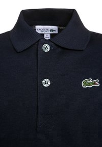 Granatowa koszulka polo wykonana z teksturowanej tkaniny, z kołnierzykiem, trzema srebrnymi guzikami i haftowanym zielonym logo krokodyla.