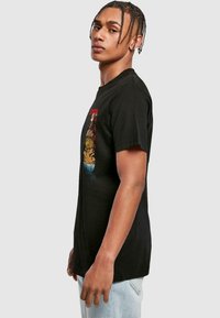 Black cotton t-shirt featuring a colorful graphic design on the front. Classic fit with short sleeves and a round neckline.