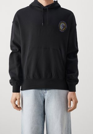 Svart huva hoodie i mjukt tyg med framficka i känguru-stil, ribbstickade ärmslut och broderad logotyp på bröstet.