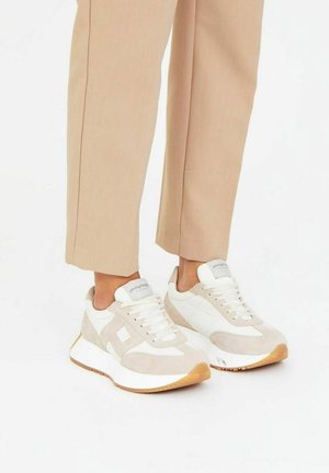 Zapatillas blancas y beige que cuentan con un upper de ante y malla, puntera redonda, suela blanca gruesa y suela exterior de goma texturizada. Con logo a modo de acento.