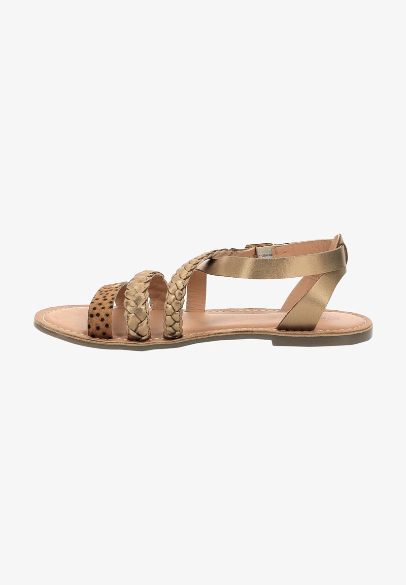 Sandale plate avec trois brides beige, deux tressées et une avec des taches noires, et une bride de cheville métallique dorée sur une semelle beige.