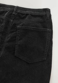 Jeans din țesătură neagră, cu o textură moale, având două buzunare pe spate și un brâu clasic cu bucle pentru curea. Coaserea laterală este vizibilă.