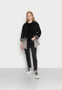 Black and gray gradient denim shirt over a black top, paired with dark jeans and white sneakers. Smooth textures and casual fit.