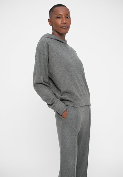 Felpa grigia con cappuccio e pantaloni abbinati realizzati in tessuto morbido. La felpa presenta un cordone e una vestibilità comoda, con tasche laterali sui pantaloni.
