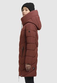 Kvadruotas tamsiai raudonas parkas su aukšta apykakle ir kapišonu. Yra juodos spalvos detalės, šoninės kišenės ir logotipo užrašas arti apačios. Sklandus paviršius.