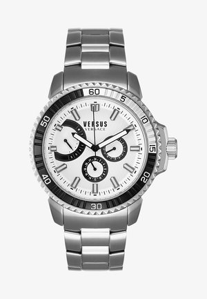 Versus Versace horloge met een zilveren roestvrij stalen band, een witte gestructureerde wijzerplaat, zwarte accenten en drie subdials met fluorescerende markeringen.
