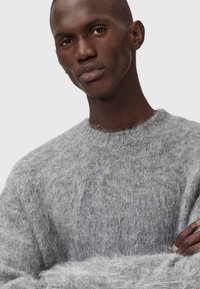 Maglione grigio e peloso realizzato in materiale morbido, con scollatura a girocollo, caratterizzato da un motivo a maglia testurizzato e maniche ampie.