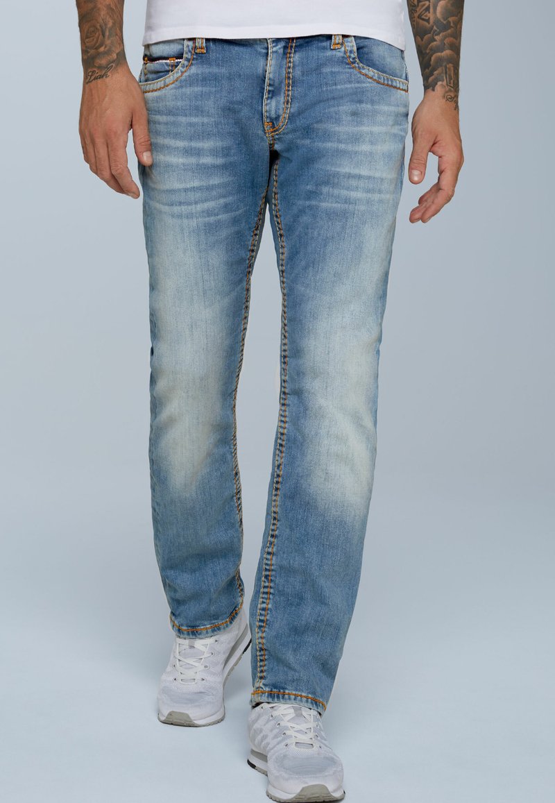 Vaqueros de denim azul claro con un acabado desgastado, diseño de pierna recta, costuras naranjas, cinco bolsillos y una cinturilla clásica con pasadores.