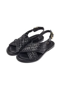Sandali in pelle intrecciata nera con design a incrocio, cinturino regolabile al tallone e suola piatta, caratterizzati da un dettaglio in fibbia dorata.