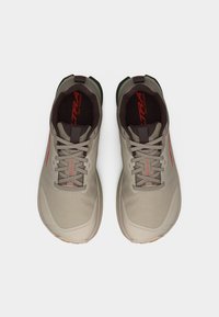 Ζευγάρι μπεζ και πράσινων παπουτσιών για τρέξιμο σε μονοπάτια με κορδόνια, σε θέα από πάνω πάνω σε λευκό απλό φόντο.