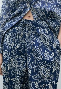 Námornícky modrý ľanový outfit s voľným blúzkou a širokými nohavicami so vzorom bielych kvetinových paisley a elastickým pásom.