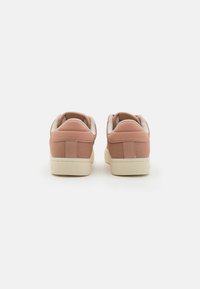 Sneaker rosa con tomaia in pelle liscia, tallone imbottito e dettagli bianchi testurizzati. Suola in gomma crema spessa e dettagli cuciti.