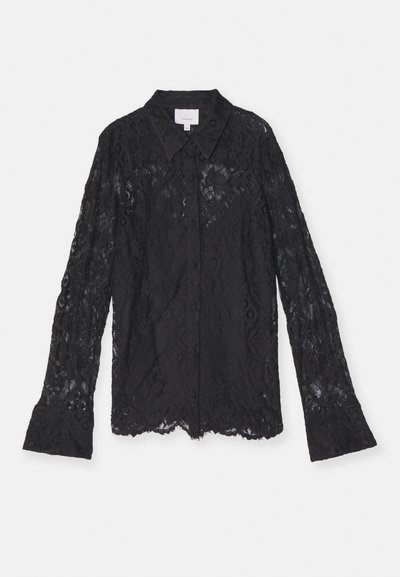 Blouse en dentelle noire avec un col, des manches longues et un motif texturé. Présente un bouton à l'avant et des poignets évasés.