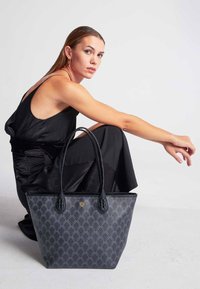 Czarna torba na ramię z plecionym wzorem w diamenty, skórzanymi akcentami i plecionymi uchwytami; pojemny design o usztywnionym kształcie.