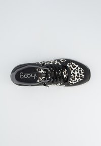 Baskets noires avec un motif léopard blanc. Présentent un tissu texturé et un design classique à lacets. Semelle en caoutchouc lisse.