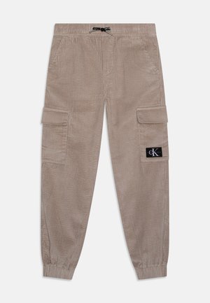 Beżowe spodnie cargo z sztruksu z elastycznymi mankietami, bocznymi kieszeniami na patki, talią ze ściągaczem i czarną naszywką z logo Calvin Klein na lewej kieszeni.