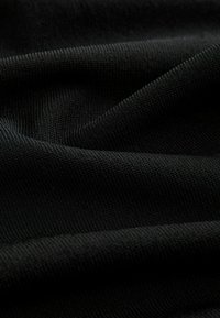 Sort strikket stof med en glat, let ribbet tekstur, der har subtile variationer i nuance og dybde.