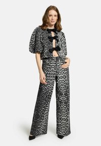 Ensemble in bianco e nero con stampa leopardata, composto da una maglietta corta a maniche puff con dettagli a fiocco e pantaloni a gamba larga e vita alta.