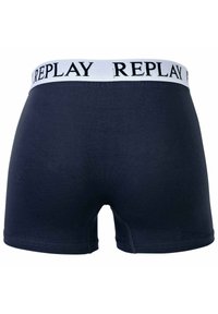 Marineblauwe boxershorts met een witte tailleband waarop het "REPLAY"-logo in het zwart is afgebeeld. Het materiaal lijkt glad, met een aansluitend ontwerp en een middellange snit.