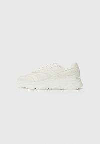 Hvit sneakers med et teksturert mesh-overdel, polstret krage, tykk s�åle med angulære linjer, og subtil merking på siden.