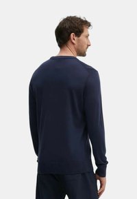 Pull en maille bleu marine avec encolure ronde, poignets et ourlet côtelés, présentant une texture lisse et un design minimaliste. Convient pour un usage décontracté.