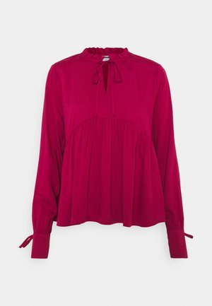 Long-sleeve, fuchsia blouse with a ruffled neckline, tie detail, and gathered bodice. Features fitted cuffs with tie closures. Soft fabric texture.
