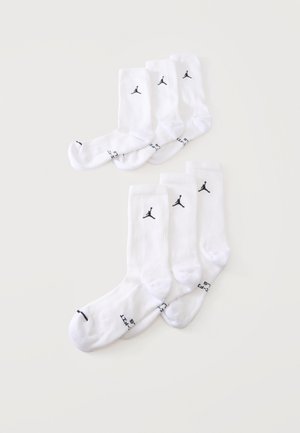 Seks par hvide crew-sokker med sorte Jumpman-logoer vist på en ensfarvet lys baggrund.