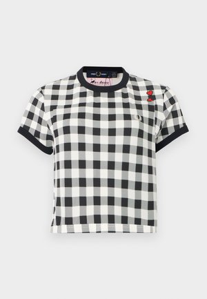 Chemise à manches courtes à carreaux noir et blanc avec col et poignets noirs, ornée de deux petites écussons en forme de cœur rouge sur la partie supérieure droite de la poitrine.