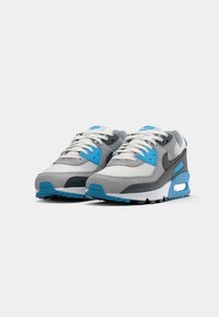 Grey and blue athletic shoes with a textured mesh upper, suede accents, and a white midsole. Features round laces and a visible air pocket.