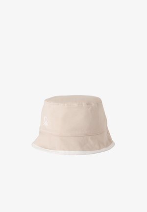 Sombrero tipo bucket beige con ribete blanco y un pequeño logo blanco bordado en el lateral, presentado sobre un fondo blanco liso.