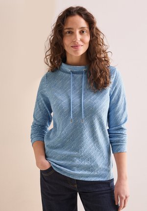 Lyseblå hættetrøje med et tekstureret mønster, med en cowl-neck og snore, lange ærmer og en afslappet pasform, parret med mørke jeans.