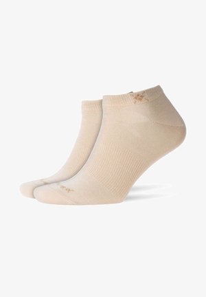 Chaussettes beiges de cheville en tissu doux et texturé. Présentent un design côtelé et un détail de logo près de la cheville. Longueur courte au-dessus de la cheville.