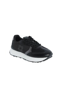 Zapatilla deportiva negra con parte superior de cuero liso y malla, que presenta una entresuela blanca, suela externa texturizada negra y acentos de logotipo.