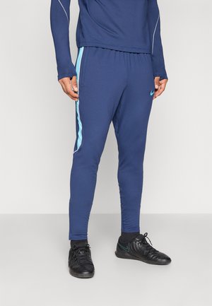 Un pantalon de sport bleu marine avec des rayures latérales bleu clair et une coupe ajustée. Confectionné dans un matériau extensible, il offre un confort optimal pour les activités physiques.