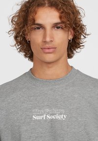 Grijze sweatshirt met een ronde hals, voorzien van witte tekst "The Future Surf Society" op de voorkant. Zacht materiaal met een casual pasvorm.