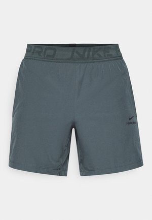 Calções atléticos cinzentos feitos de tecido leve, com uma cintura elástica com "NIKE PRO" impresso e um pequeno logótipo na lateral.